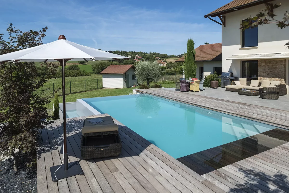 Piscine à débordement sur deux côtés, plage et margelles en bois
