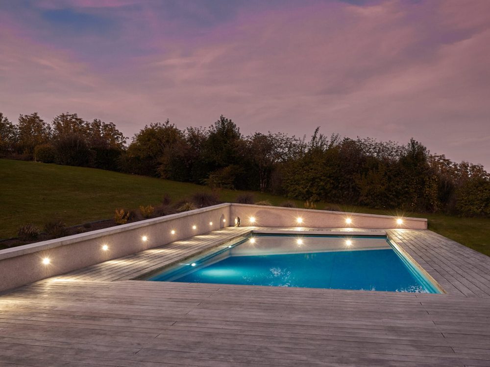 Piscine extérieure de 11 x 4.5 m avec spot leds et plage en bois exotique